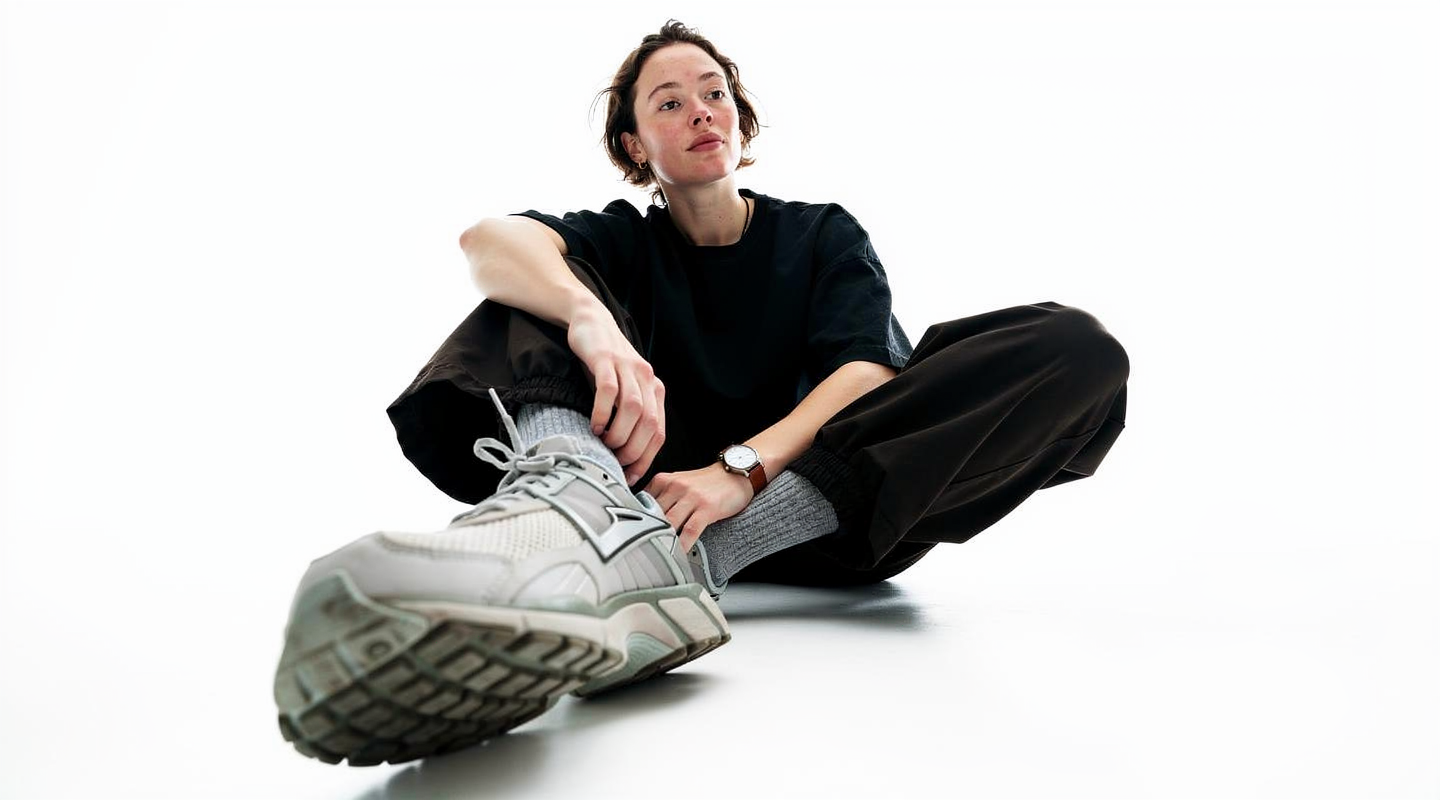 Woman seated on the floor, one sneaker toward the camera