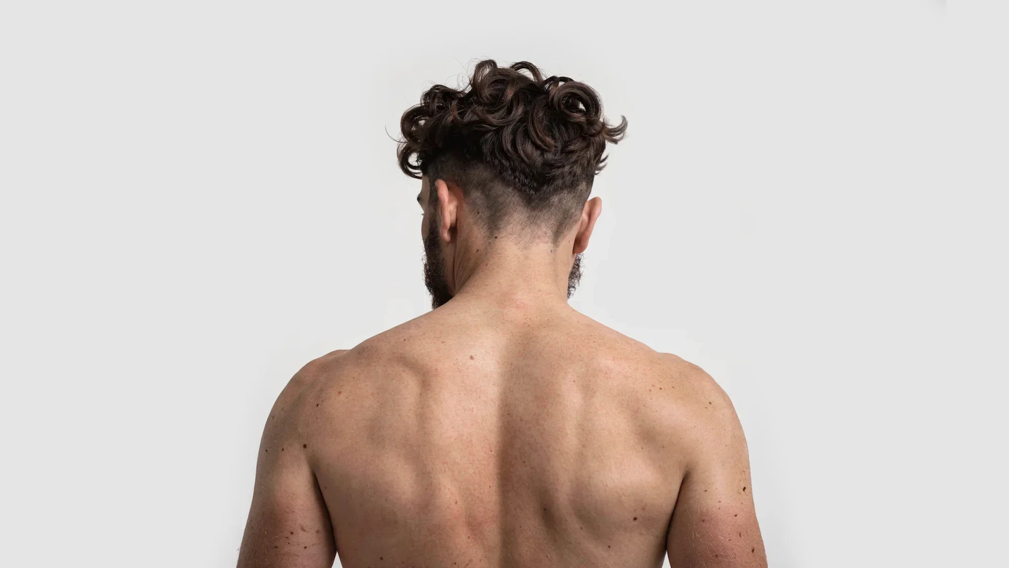 AI-generated view of the same fictional man from behind, showing his back, shoulders and the back of his head