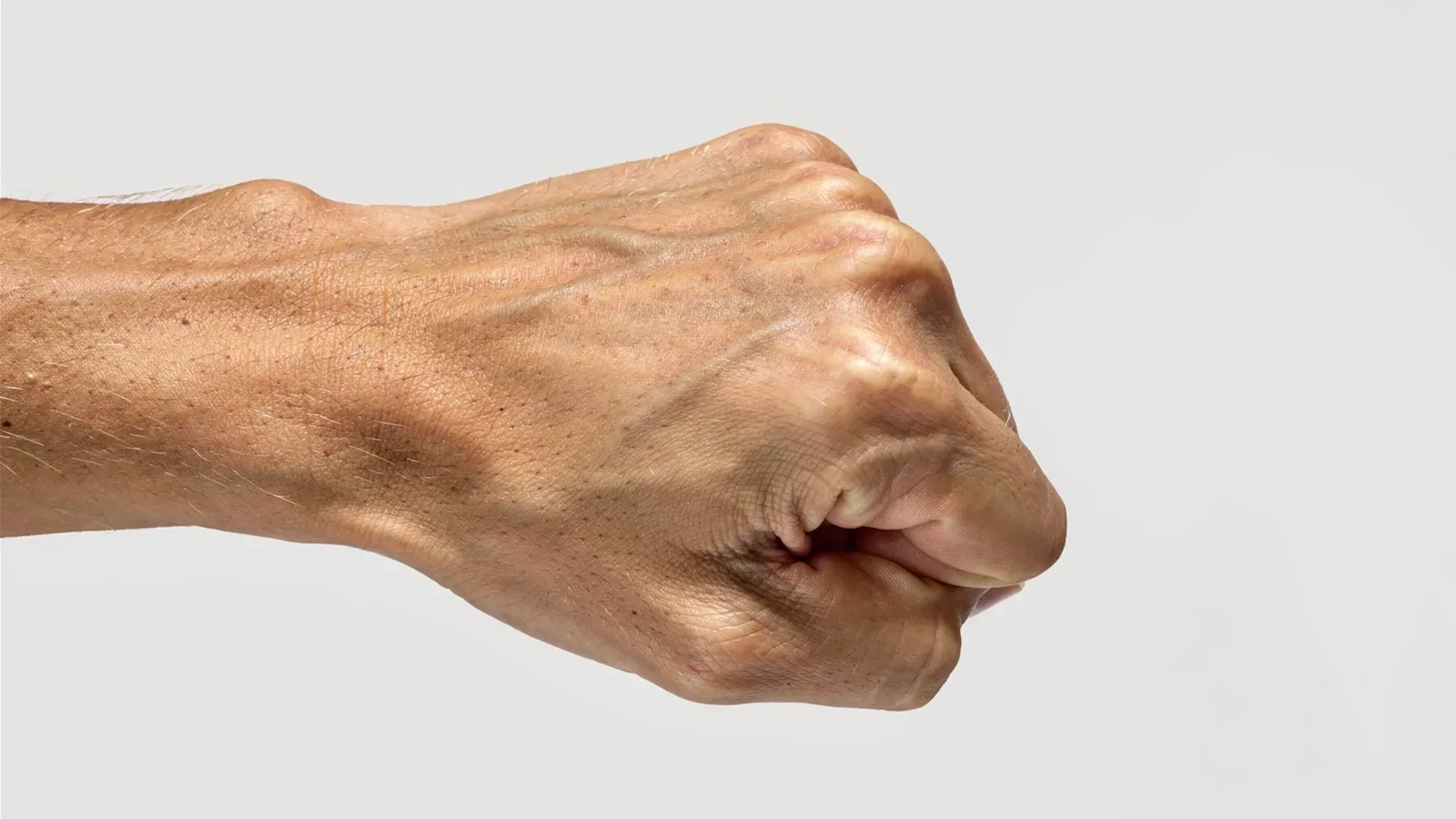 AI-generated close view of a closed fist and forearm seen from the side against a light grey background