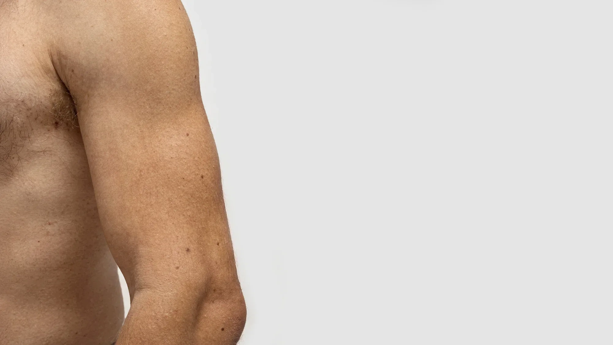 AI-generated close view of a bare arm and side of the chest with empty space beside it for placing a product