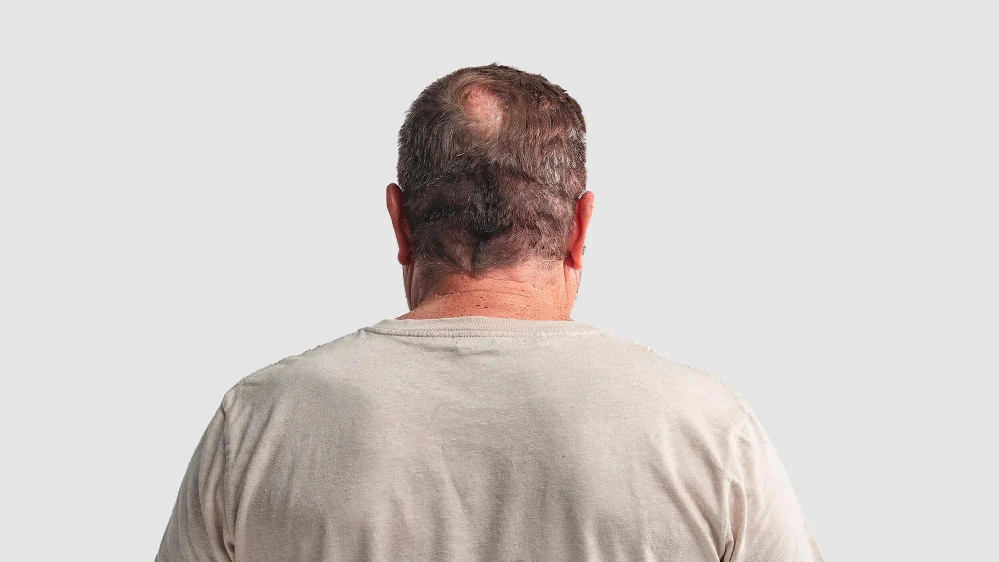 AI-generated view of the same fictional older man from behind, showing thinning hair, neck and the back of a worn cream t-shirt