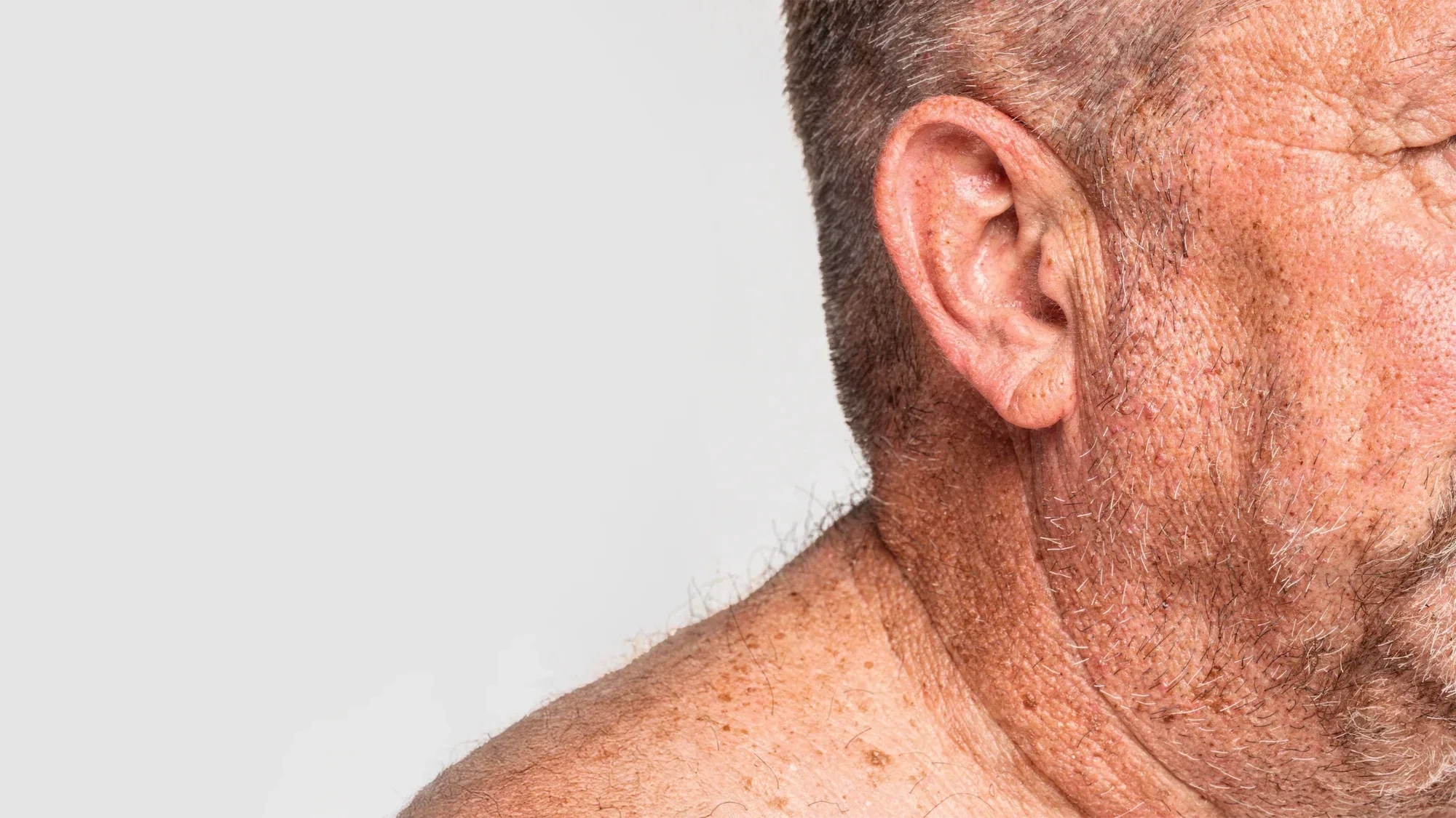 AI-generated close view of an ear, jaw and shoulder with visible skin texture and open space beside it for placing a product