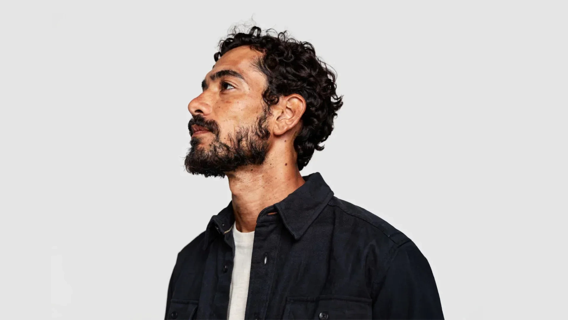 AI-generated three-quarter view of the same fictional man looking upward, showing moles and skin texture on his neck