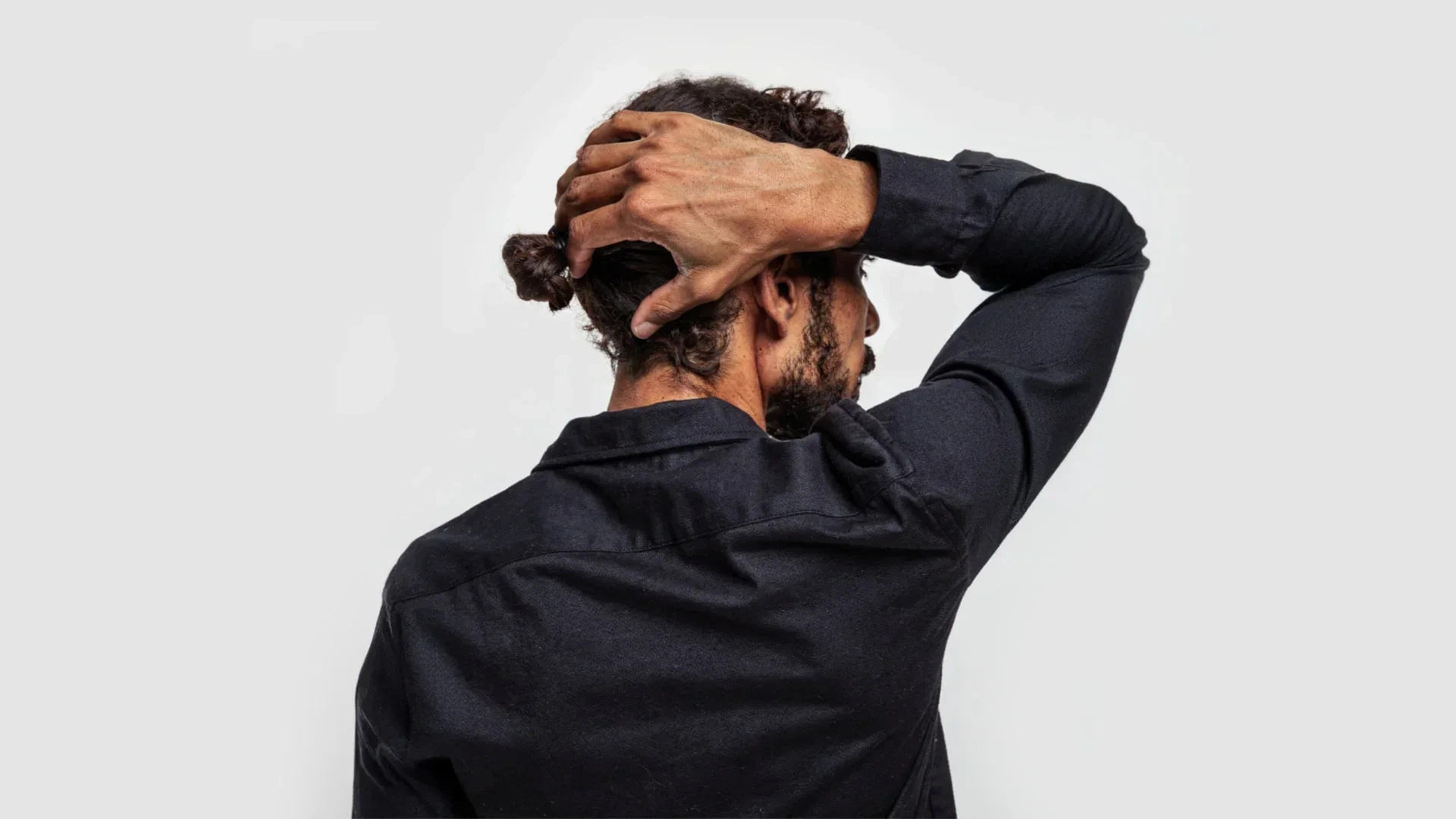 AI-generated view of the same fictional man from behind with one hand reaching to the back of his head